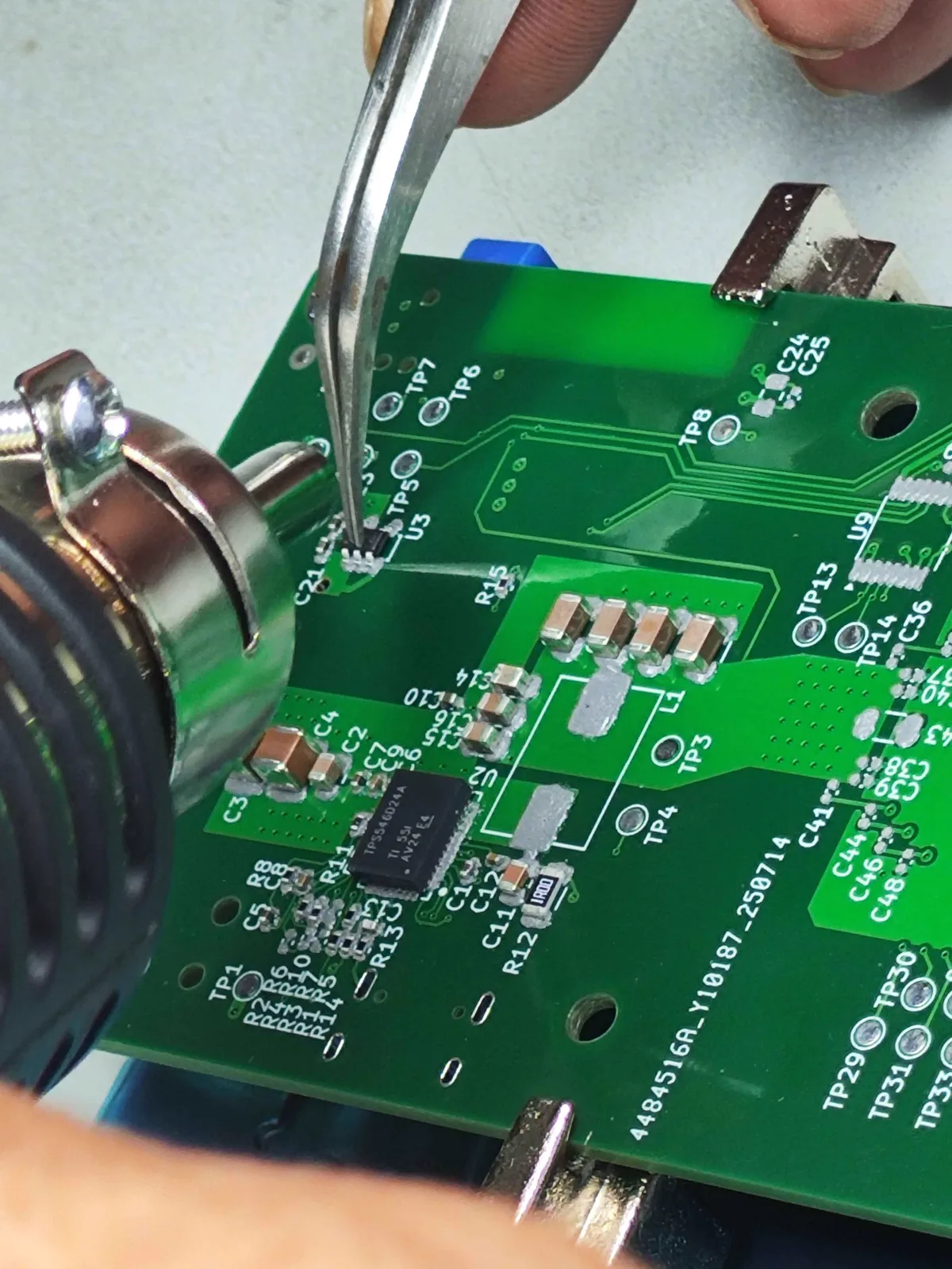 Hands soldering a Bitaxe circuit board during a repair